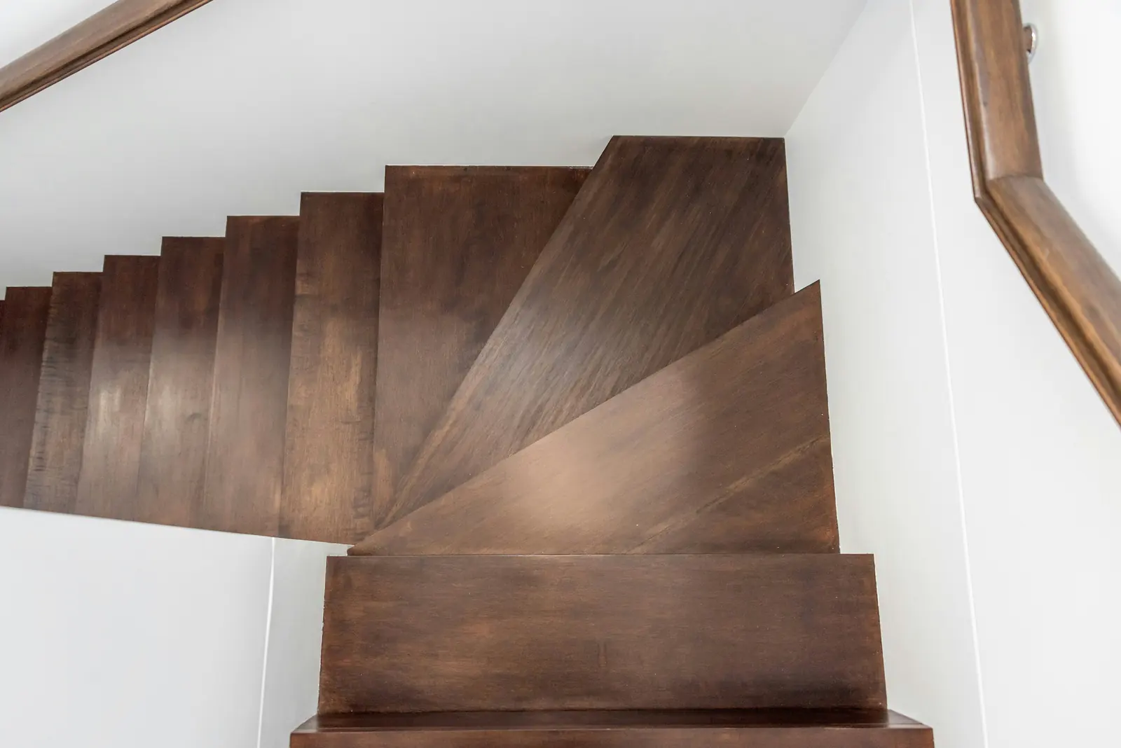 Dark stained wood staircase with matching treads, risers and handrail