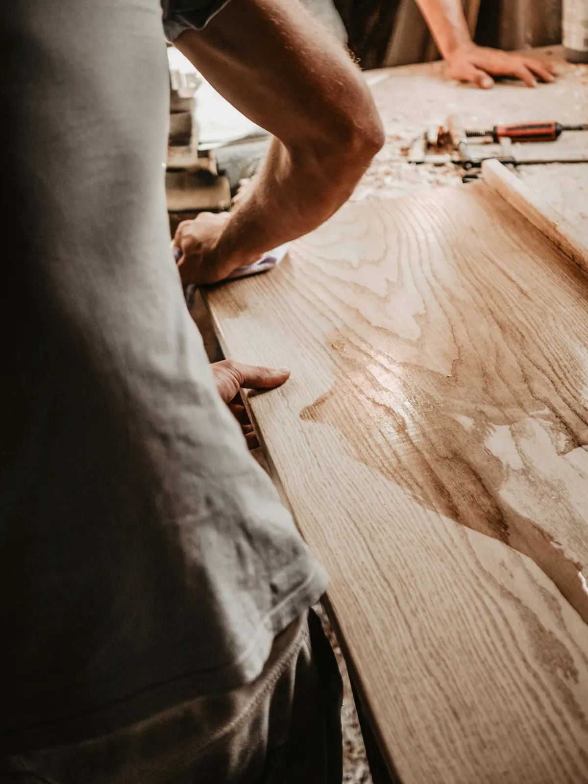 Craftsman finishing a new oak board to match an existing hardwood floor